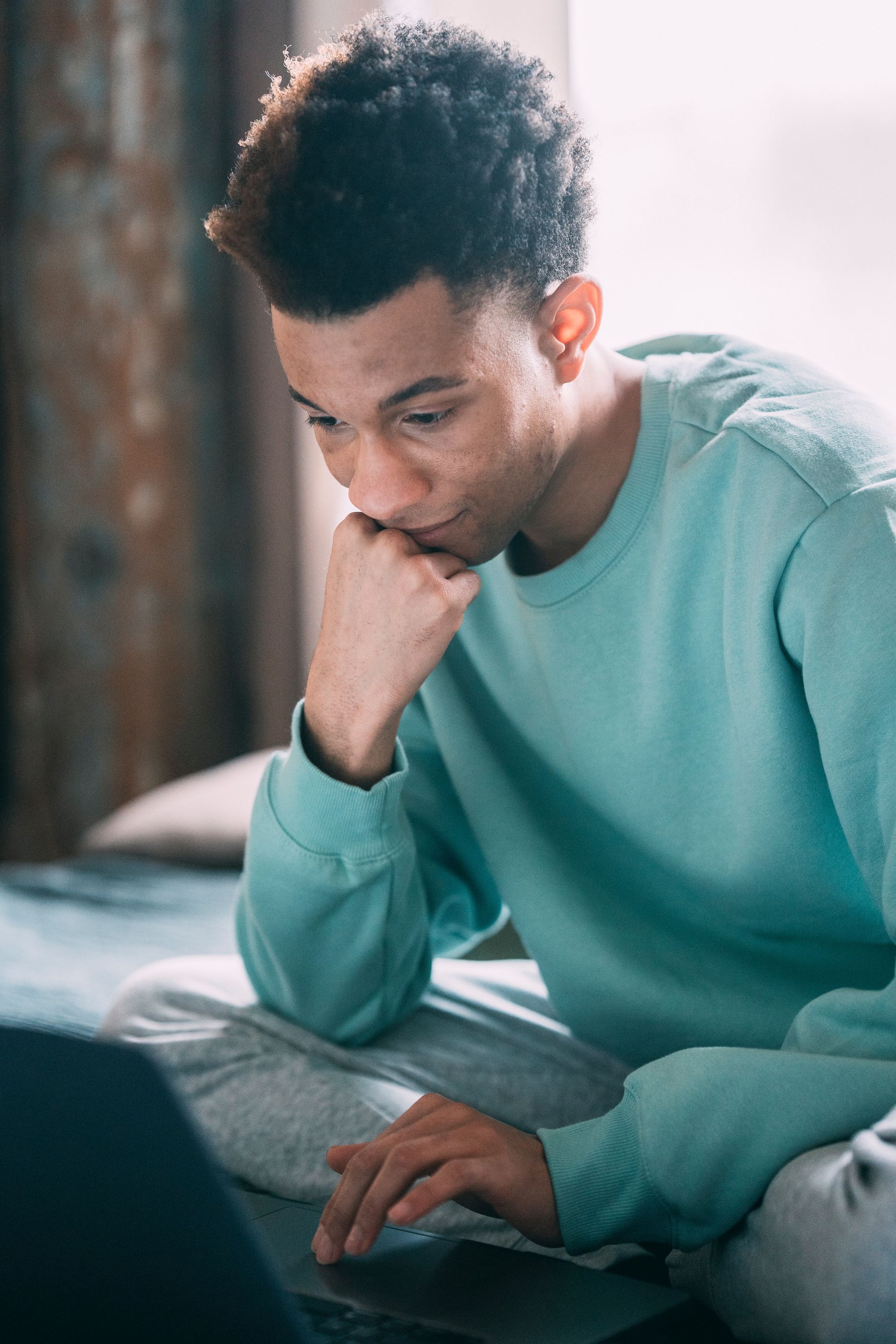 Thinking casual professional young man staring at his laptop.